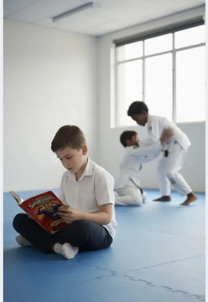 Chico leyendo Jóvenes Súper Estoicos en un tatami mientras otros entrenan judo